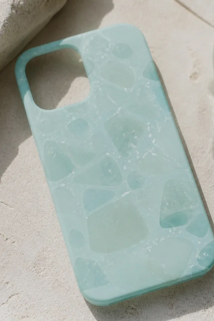 A pale aqua phone case with translucent-looking patches and tiny white speckles, like sea glass smoothed by waves.