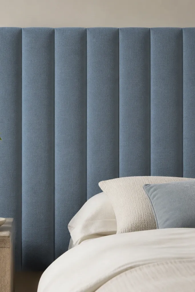 A headboard with straight vertical channels, evenly spaced, with thin piping lines separating each channel. The fabric is dusty blue, and the channels look crisp from top to bottom.