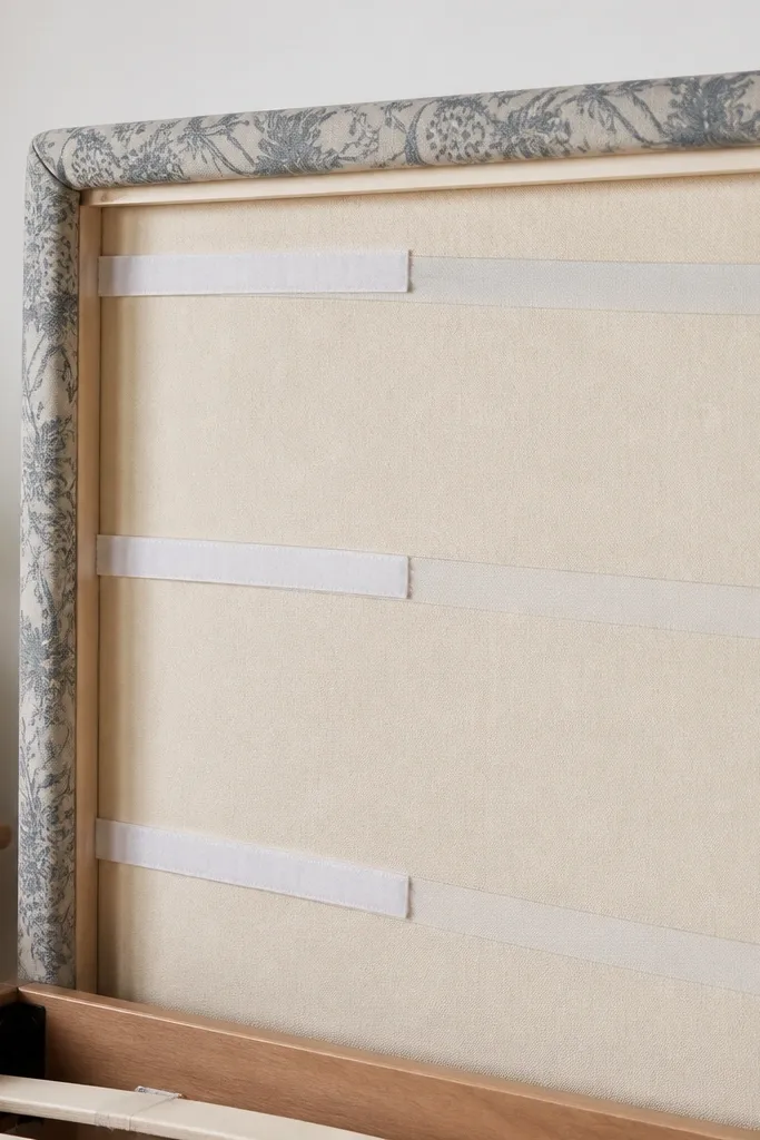 A headboard covered in patterned cotton fabric stretched tight across a backing board. Behind the fabric, you can see soft Velcro straps that hold it in place without stitching.