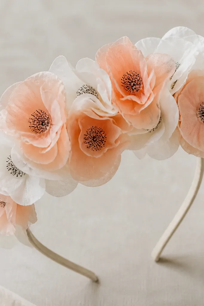 A flower crown made from stacked coffee filters, each flower painted pale peach and white with a stamped center made from a sponge and dark ink. The crown sits on a headband base.